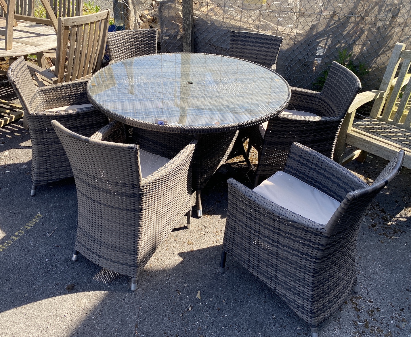 An all weather circular rattan garden table and six chairs with seat cushions, table 136cm diameter, height 75cm